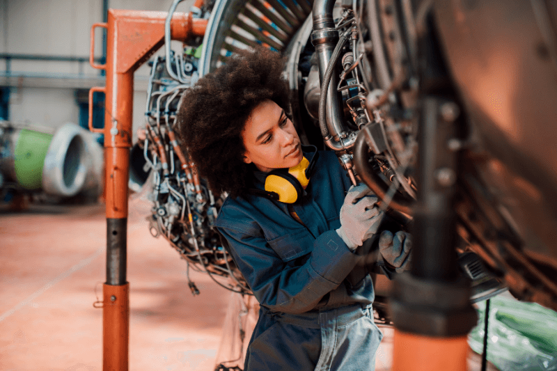 An aerospace recruitment employee works on a mechanical parts of a plane.