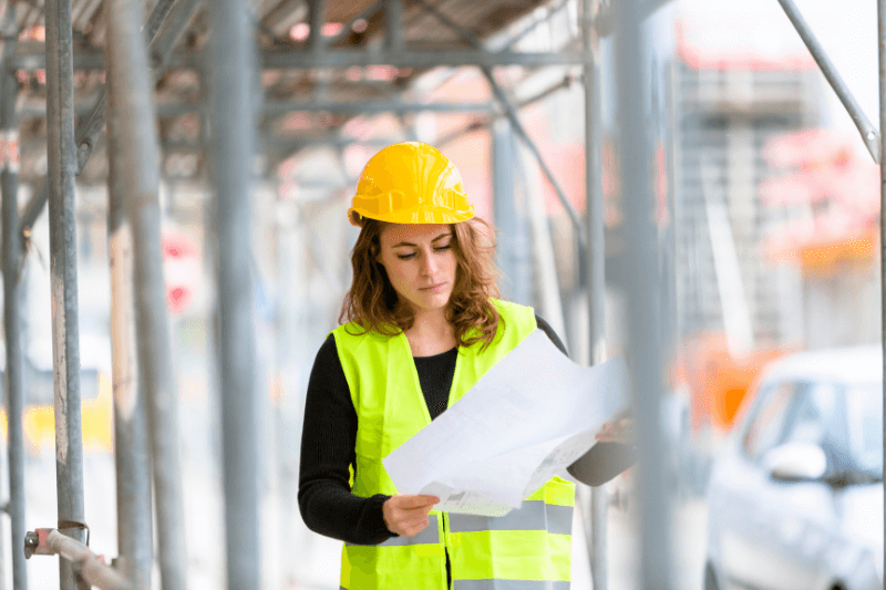 A light industrial staffing hire walks through the jobsite while examining a document.