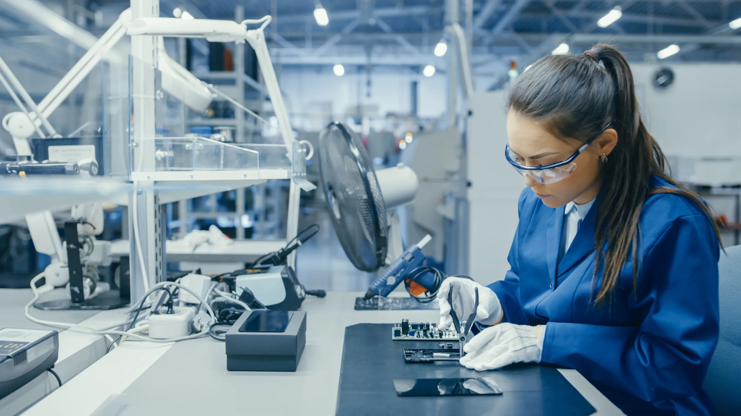 Semiconductor Recruiters Hire Works At Desk An employee hired by expert semiconductor recruiters uses tools to work on a manufacturing project at a desk.