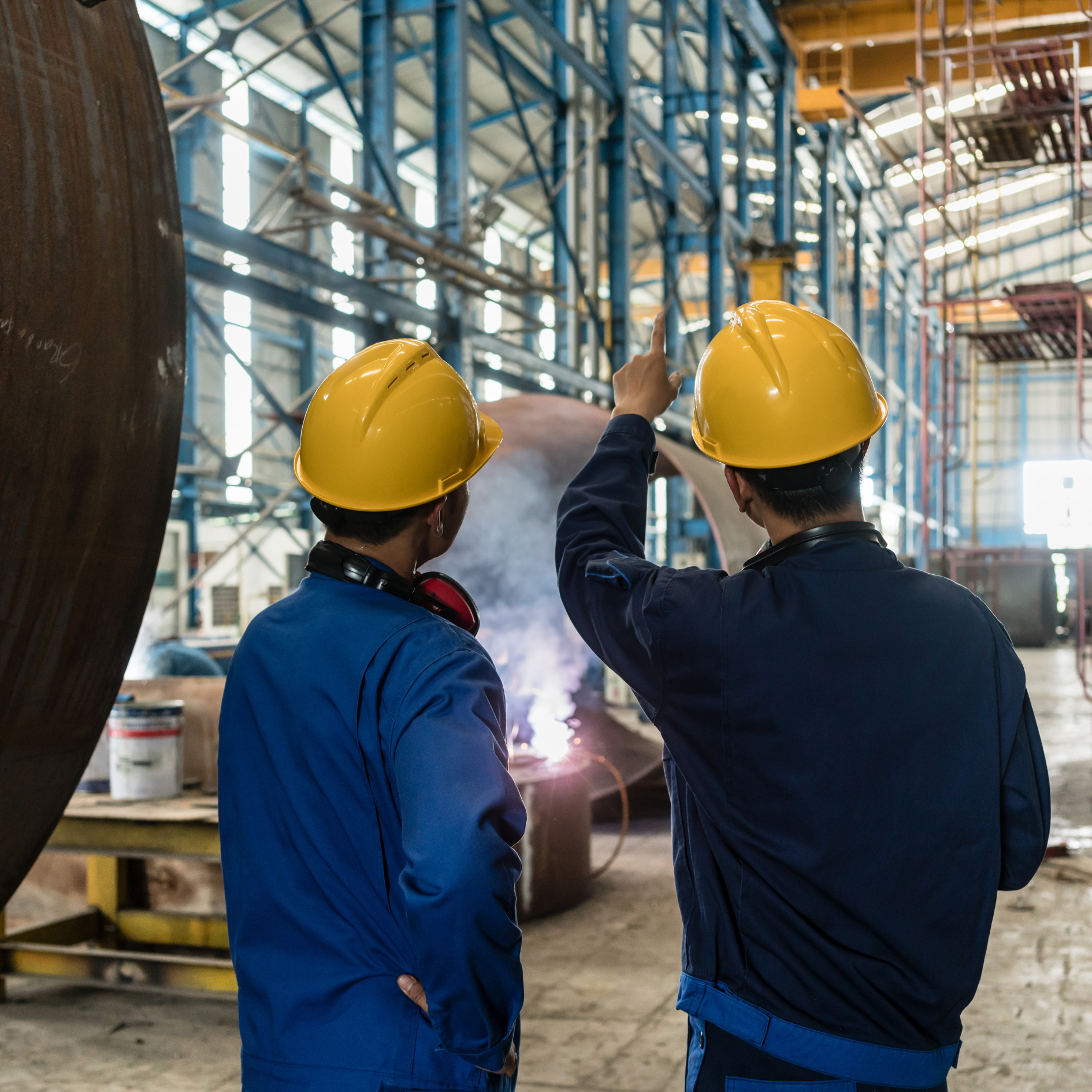 Industry Partner Two light industrial staffing solutions hires in hardhats and safety vests pointing at the jobsite.